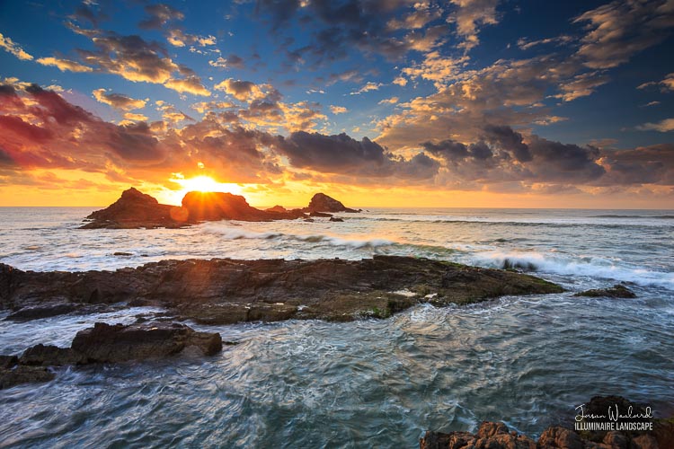 The sun bursts under the clouds over the '3 Sisters' rocks Broken Head, North Coast, New South Wales, Australia - Jason Woolard