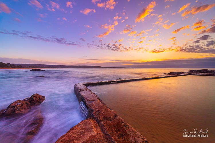 Sunrise lights the speckled clouds over the Aslings Beach Rock Pool, the soft water in the pool a balance to the rushing waves outside. Landscape photography