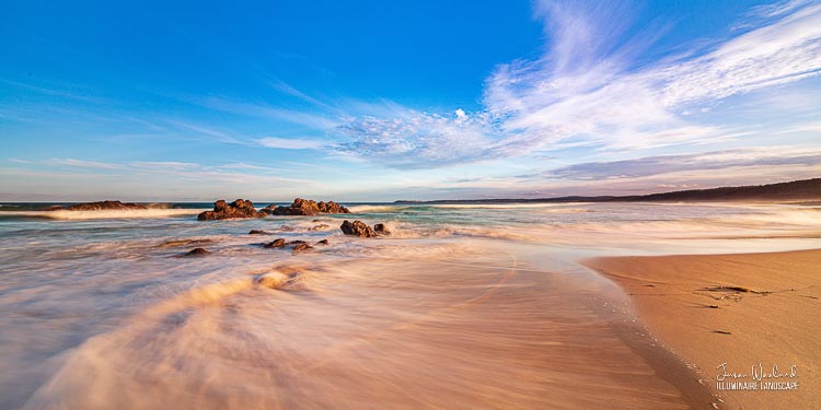 The clouds and the waves create beautiful swooshing lines around the rocks. Haywards Beach near Bermagui, New South Wales.