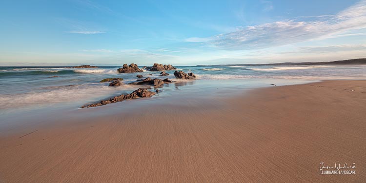 Subtle lines in the sand all point to the dramatic water swirling around the rocks. Haywards Beach, Wallaga Lake, New South Wales - landscape photography